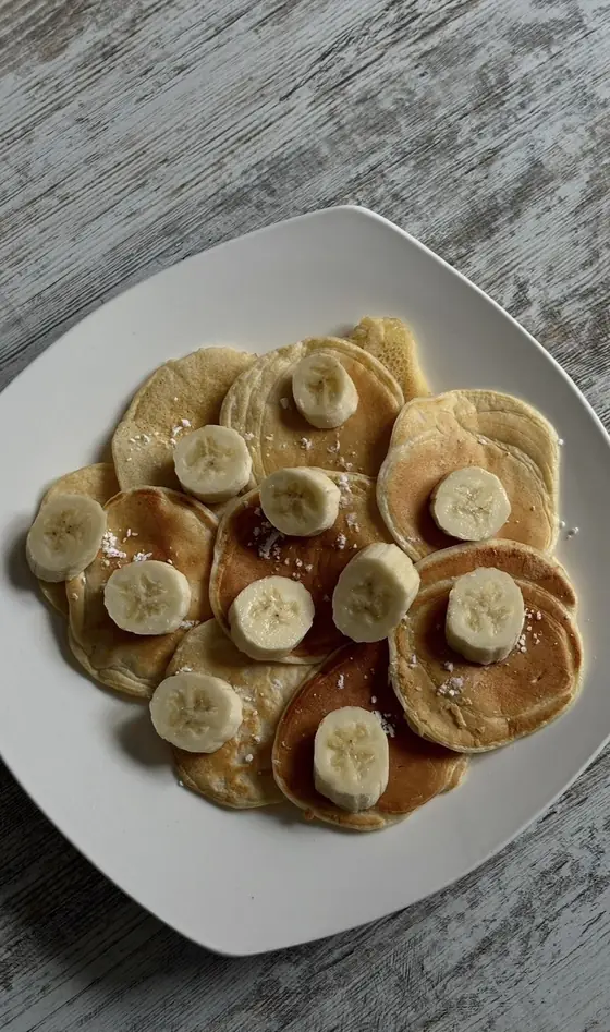 Een bord kleine pannenkoeken met schijfjes banaan
